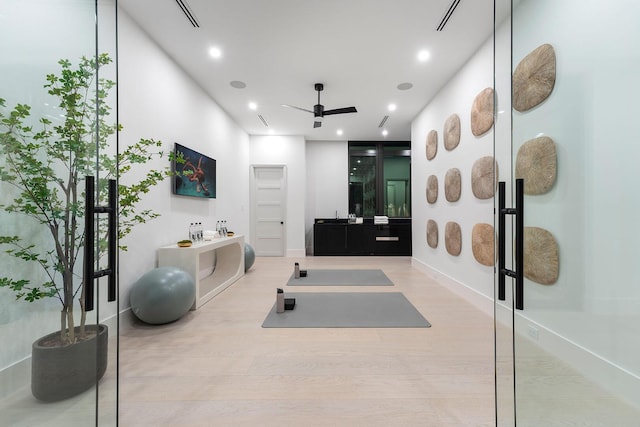 exercise room with ceiling fan and light hardwood / wood-style floors