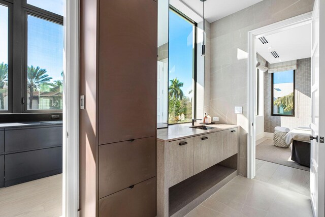 bathroom featuring tile patterned flooring, vanity, and tile walls