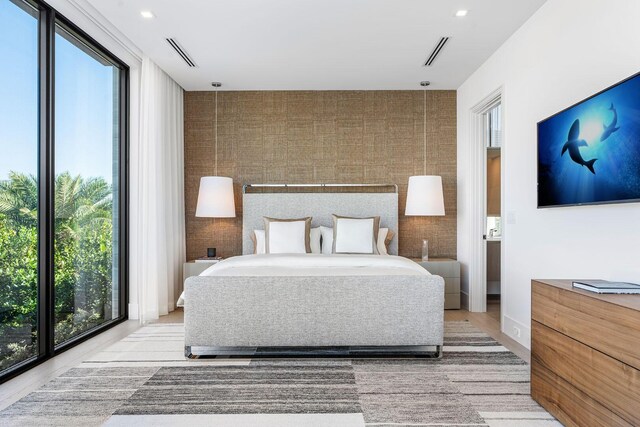 bedroom with floor to ceiling windows, access to exterior, and light hardwood / wood-style floors