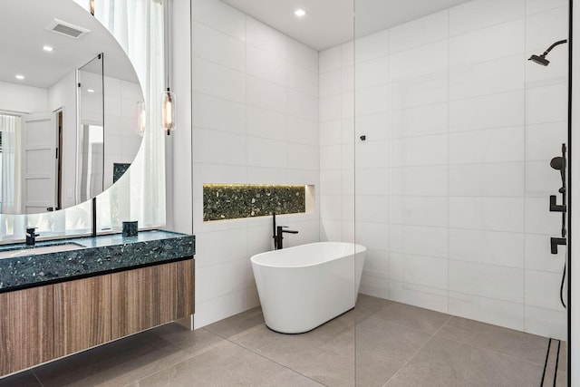 bathroom with vanity, shower with separate bathtub, and tile walls