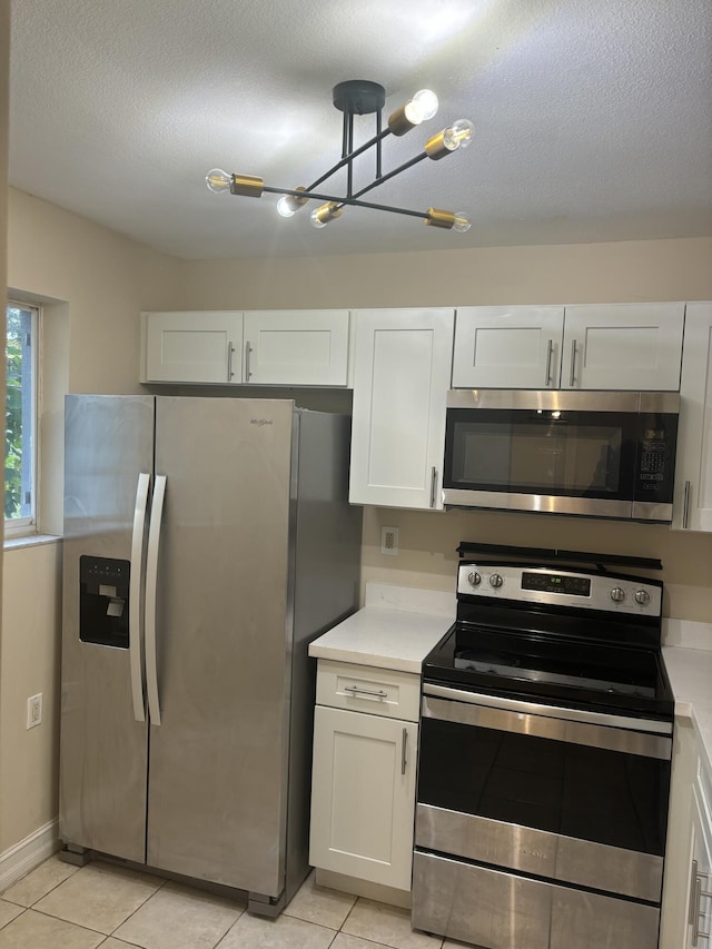 kitchen featuring white cabinetry, an inviting chandelier, a textured ceiling, light tile patterned flooring, and appliances with stainless steel finishes