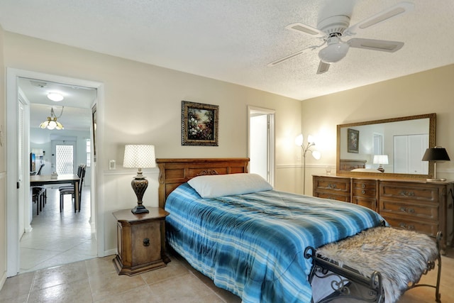 tiled bedroom with ceiling fan and a textured ceiling