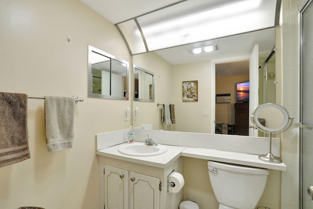 bathroom featuring vanity, a shower with shower door, and toilet