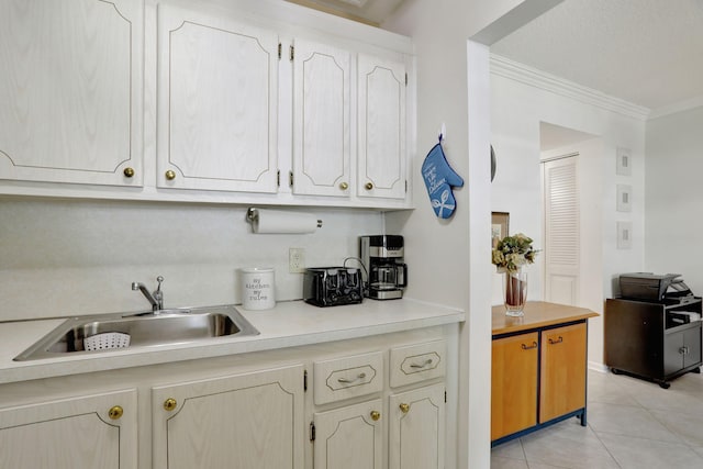 kitchen featuring light tile patterned flooring, crown molding, and sink