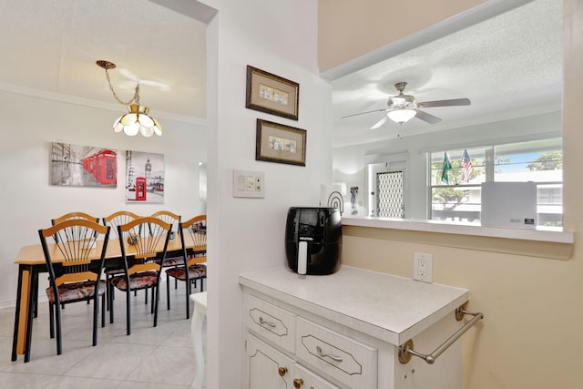 kitchen featuring crown molding, a textured ceiling, decorative light fixtures, light tile patterned floors, and ceiling fan with notable chandelier