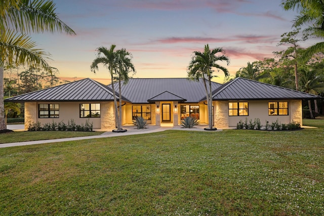 back house at dusk featuring a lawn