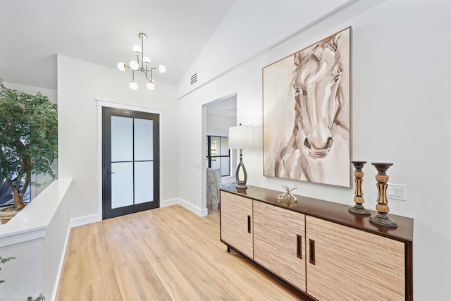 entryway featuring a notable chandelier, lofted ceiling, and light wood-type flooring