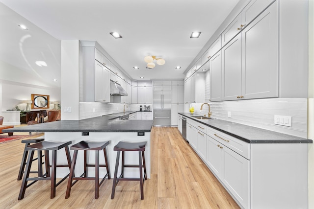 kitchen with kitchen peninsula, a breakfast bar, stainless steel dishwasher, and sink