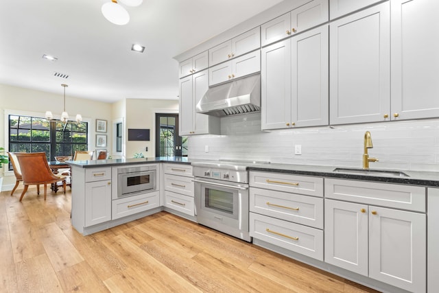 kitchen featuring built in microwave, sink, stainless steel range oven, decorative light fixtures, and decorative backsplash