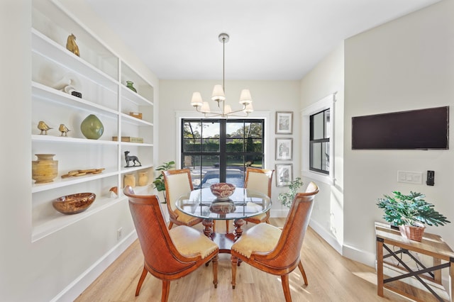 dining space featuring a notable chandelier, light hardwood / wood-style floors, and built in shelves