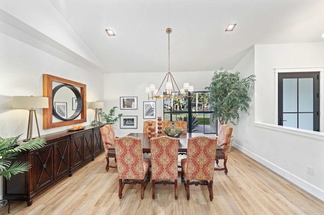 dining room with light wood-type flooring, vaulted ceiling, and a notable chandelier