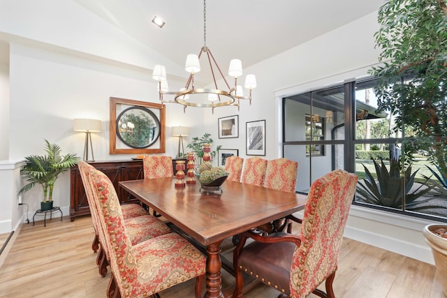 dining area featuring an inviting chandelier, light hardwood / wood-style flooring, and vaulted ceiling