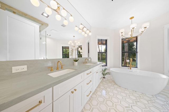 bathroom featuring tile patterned flooring, a notable chandelier, a bathtub, and vanity