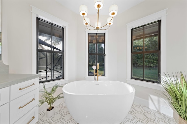 bathroom with a notable chandelier, a washtub, and vanity