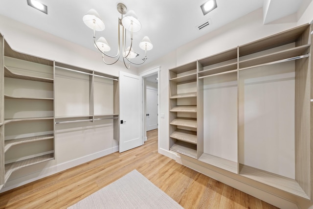 spacious closet featuring a notable chandelier and wood-type flooring