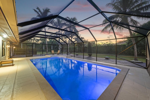 pool at dusk featuring a patio area and a lanai