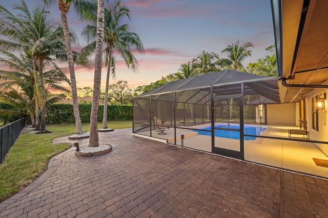 patio terrace at dusk featuring a fenced in pool and a yard