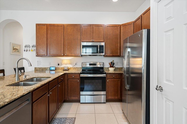 kitchen with light stone counters, light tile patterned floors, sink, and appliances with stainless steel finishes