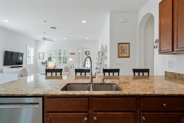 kitchen featuring light stone counters, sink, ceiling fan, and stainless steel dishwasher