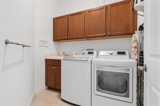 laundry room with washer and clothes dryer, cabinets, light tile patterned floors, and sink