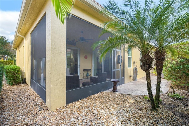 view of side of home featuring a sunroom and ceiling fan