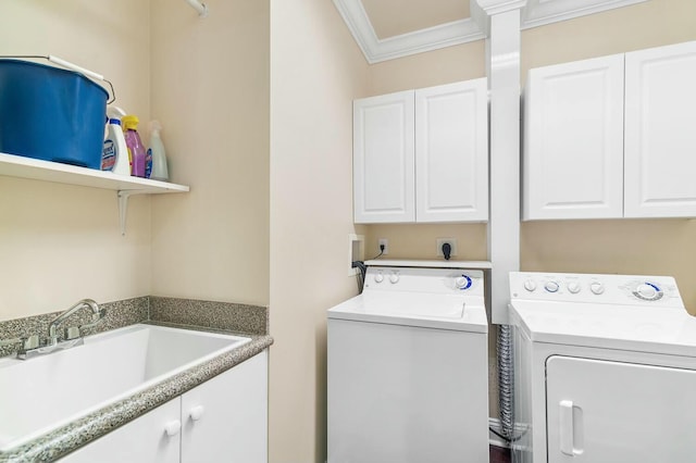 laundry room featuring cabinets, crown molding, sink, and washing machine and clothes dryer