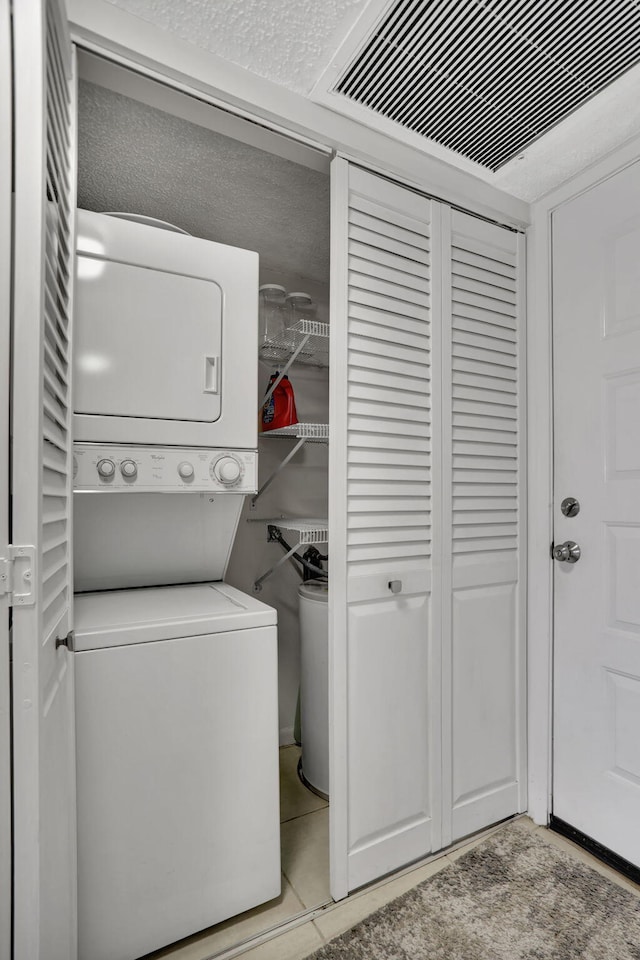 washroom with light tile patterned floors and stacked washing maching and dryer