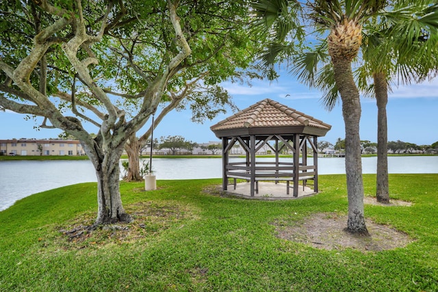 view of dock with a gazebo, a lawn, and a water view