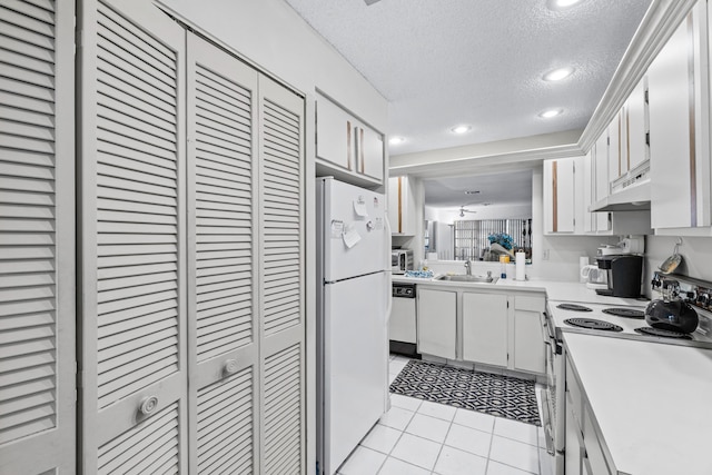 kitchen featuring white cabinetry, sink, a textured ceiling, white appliances, and light tile patterned floors