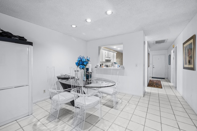 unfurnished dining area featuring light tile patterned floors and a textured ceiling