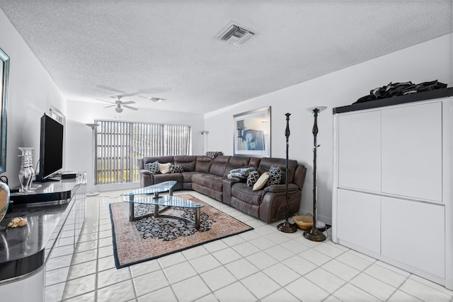 living room featuring ceiling fan, light tile patterned flooring, and a textured ceiling