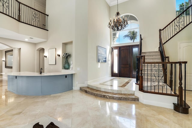 entrance foyer featuring a chandelier, a high ceiling, ornamental molding, and sink