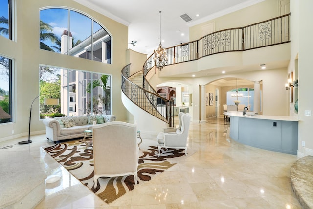 interior space featuring a towering ceiling, decorative columns, crown molding, sink, and an inviting chandelier