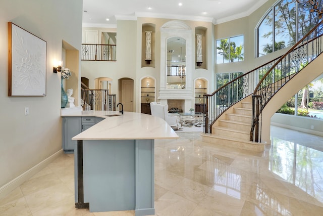 kitchen with gray cabinets, light stone counters, sink, and ornamental molding