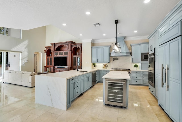 kitchen with hanging light fixtures, wine cooler, kitchen peninsula, a kitchen island, and custom range hood