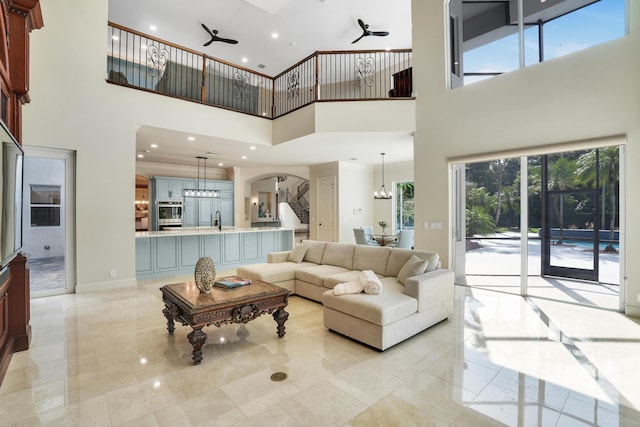 living room featuring ceiling fan with notable chandelier and a towering ceiling