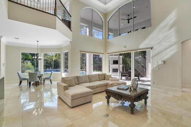 living room with ceiling fan with notable chandelier, a towering ceiling, and ornamental molding