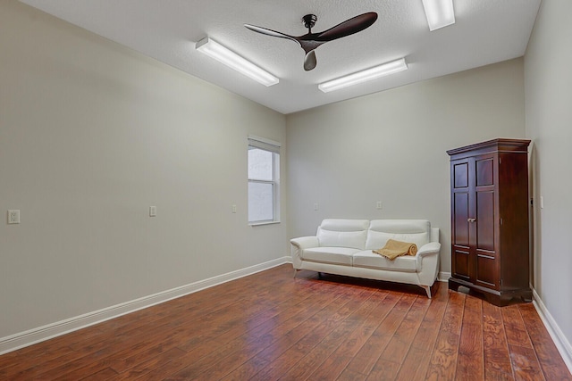 living area featuring ceiling fan, dark wood-type flooring, and a textured ceiling