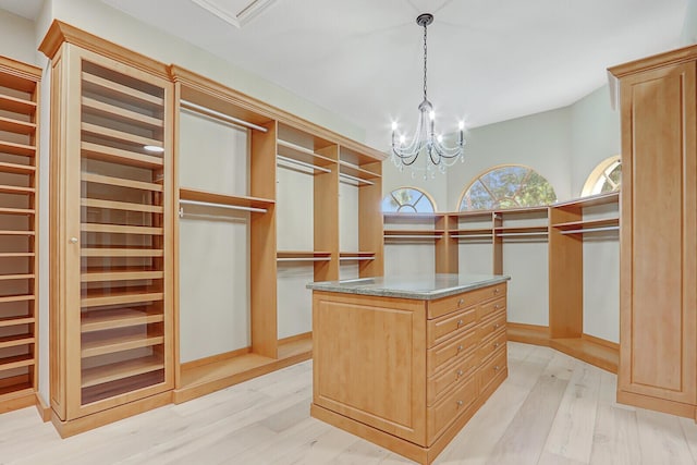 walk in closet featuring light hardwood / wood-style floors and an inviting chandelier