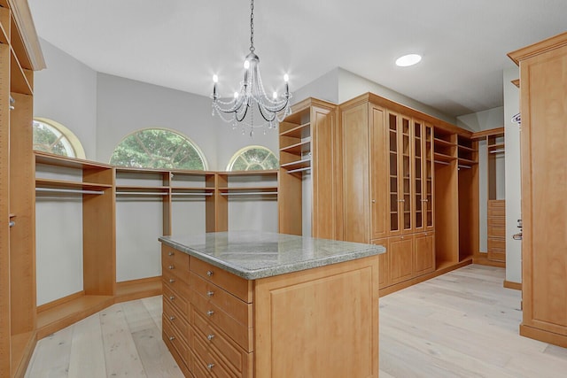 spacious closet with a notable chandelier and light wood-type flooring