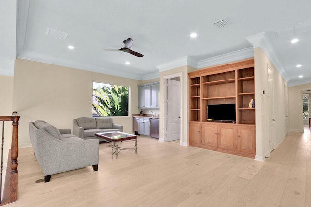 living room with ceiling fan, sink, light wood-type flooring, and crown molding