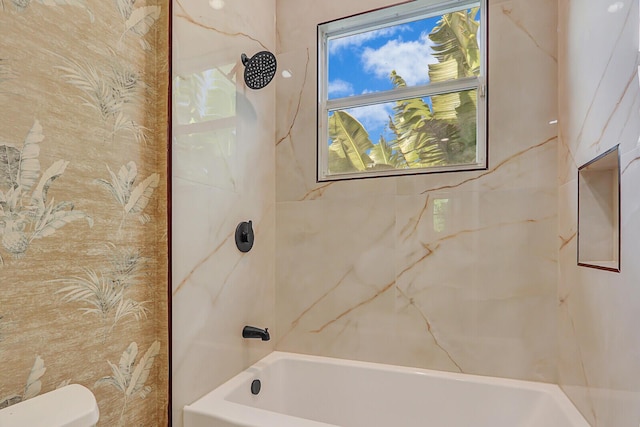 bathroom featuring tiled shower / bath combo and toilet