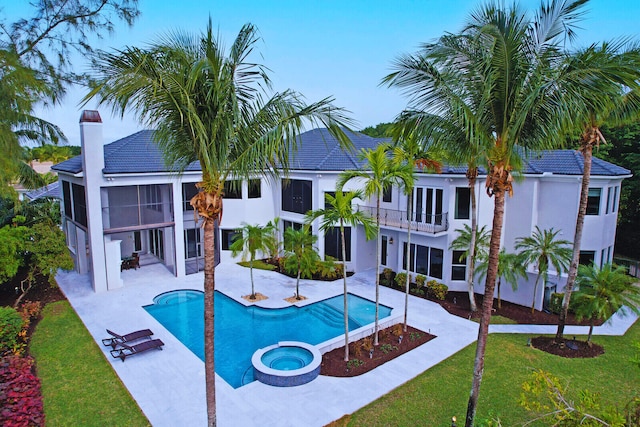 view of swimming pool with an in ground hot tub, a sunroom, a patio area, and a lawn