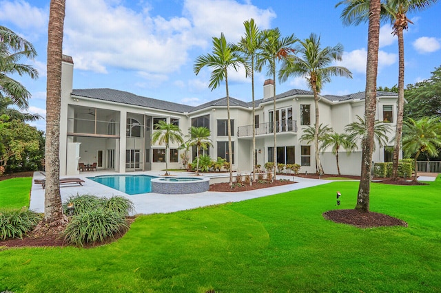 rear view of house with a yard, a balcony, a patio, and a pool with hot tub