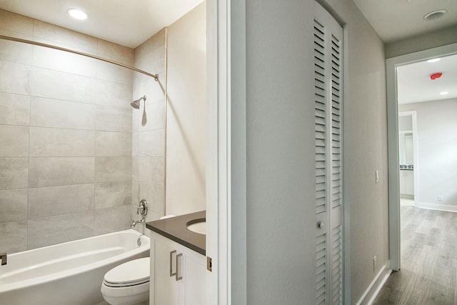 full bathroom featuring vanity, hardwood / wood-style flooring, toilet, and tiled shower / bath combo