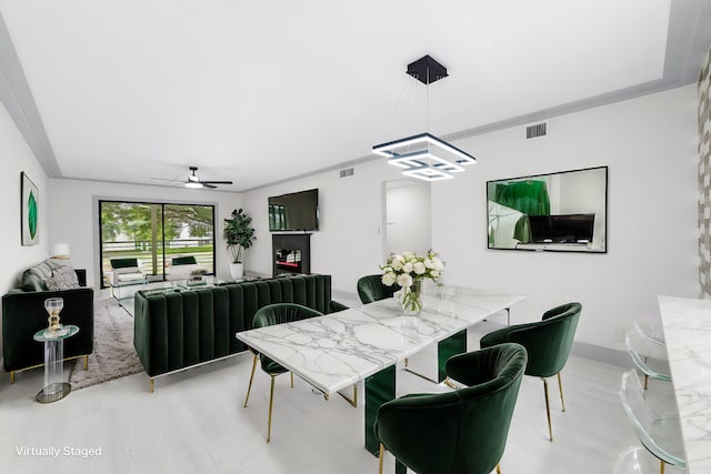 dining area with ceiling fan with notable chandelier, wood-type flooring, and ornamental molding