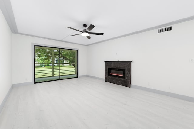 unfurnished living room featuring a high end fireplace, light wood-type flooring, ceiling fan, and crown molding