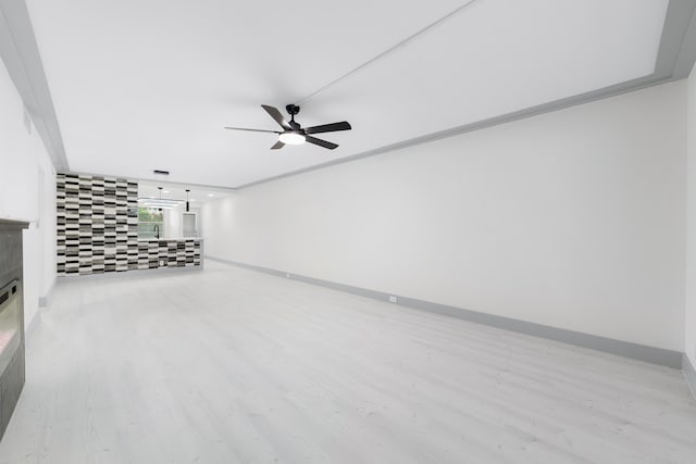 unfurnished living room featuring a tiled fireplace, ceiling fan, light hardwood / wood-style floors, and ornamental molding