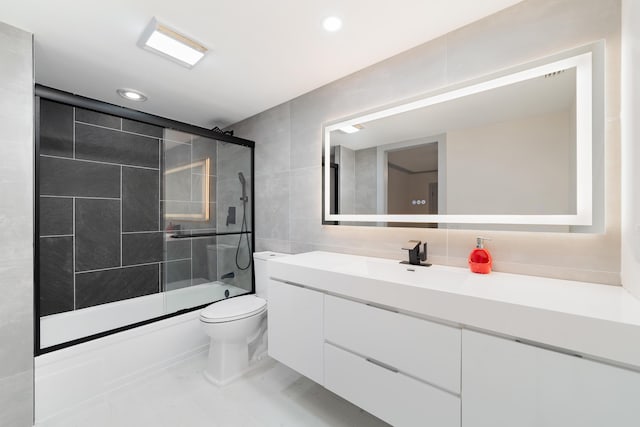 full bathroom featuring combined bath / shower with glass door, vanity, and toilet