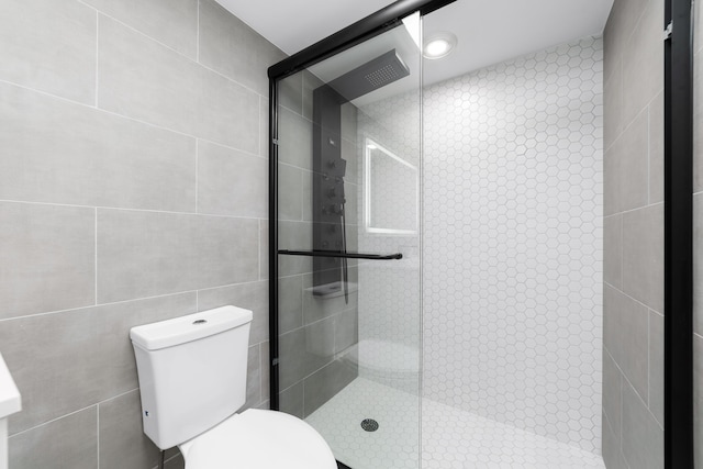 bathroom with an enclosed shower, toilet, and tile walls